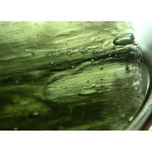 Fotografía microscópica de piedra moldavita auténtica mostrando líneas de flujo Schlieren