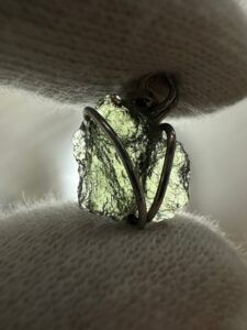 Pieza única de colección (Ref: MMJ14A-3). Este colgante de moldavita auténtica en bruto ha sido seleccionado por su excepcional escultura natural. Incluye vídeo real del ejemplar y garantía de autenticidad mediante análisis microscópico de lechatelierita realizado por nuestro geólogo y gemólogo. Recibe exactamente la pieza que ves en las fotos