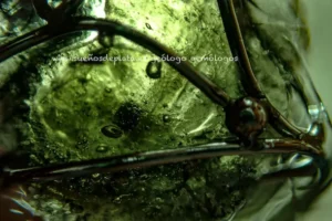 Inclusiones internas en moldavita auténtica observadas al microscopio con burbujas de gas irregulares y estructura vitrea natural